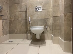 Bathroom features a toilet, handheld showerhead, and wall-mounted mirror.