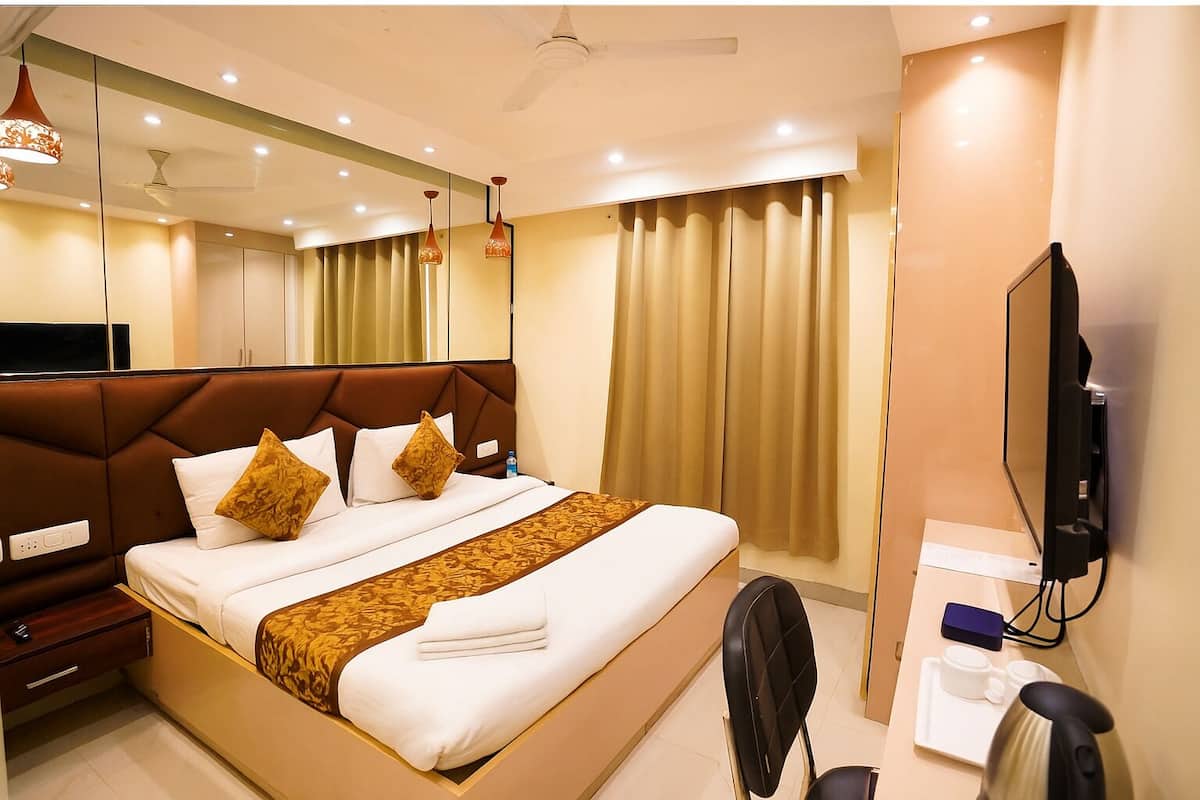 A hotel room with a large bed, a desk with a chair, a TV, and a coffee maker.