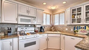 A kitchen with white cabinets, a stove, and a microwave.