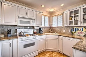 Une cuisine avec des meubles blancs, une cuisinière et un four à micro-ondes.