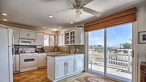 A kitchen with white cabinets, a central island, and a large sliding glass door leading to a balcony.