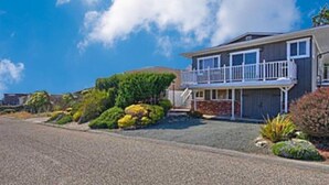 A two-story house with a balcony, a driveway, and well-maintained landscaping.