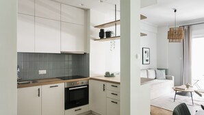 A modern kitchen with white cabinetry, a built-in oven, and a grey backsplash.