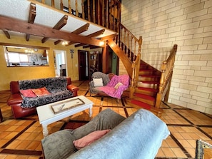 A spacious living area with a staircase, a sofa, a coffee table, and a dining area. - House a few steps from the beach G0108 (Hourtin)