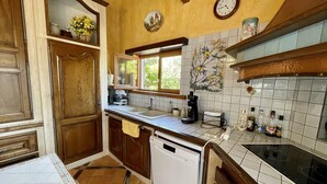 A kitchen with wooden cabinets, a dishwasher, a stove, and a window. - Gemütliches Haus mit Schöner Terrasse - Ganz Strandnah! (Hourtin)