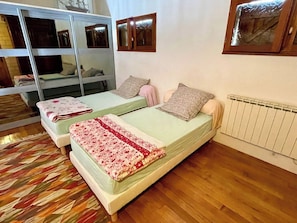 Una habitación con dos camas, un radiador y una ventana.