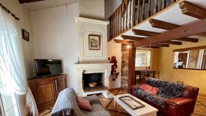 A cozy living room with a fireplace, a sofa, a television, and a staircase. - Gemütliches Haus mit Schöner Terrasse - Ganz Strandnah! (Hourtin)