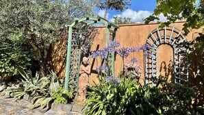 A garden with a pergola, stone pathway, and a variety of plants. - Gemütliches Haus mit Schöner Terrasse - Ganz Strandnah! (Hourtin)
