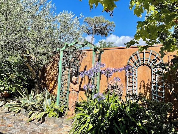 A garden with a statue, a pergola, and a wall with a window. - House a few steps from the beach G0108 (Hourtin)