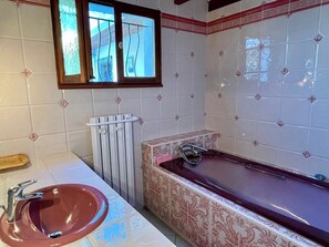 Un baño con lavamanos, bañera y ventana.