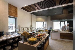 Ein reichhaltiges Buffet mit verschiedenen Speisen und ein Koch, der im Hintergrund kocht.