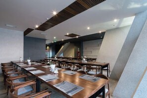A modern conference room with long tables, chairs, and a staircase in the background.