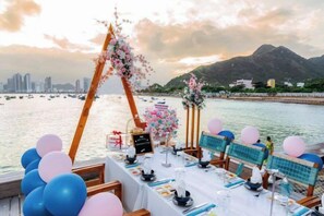 A waterfront dining setup with tables, chairs, and a decorative arch. - Joy Trip Hotel & Spa Nha Trang (Nha Trang)