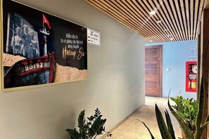 A hallway with a large poster, a wooden ceiling, and a door at the end.