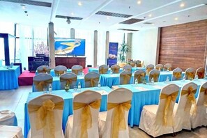 A banquet hall with tables set for a formal event, featuring rows of chairs with sashes and tables with centerpieces. - Joy Trip Hotel & Spa Nha Trang (Nha Trang)