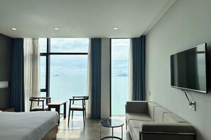 Une chambre d’hôtel avec un lit, un canapé, une télévision, une petite table et des chaises.