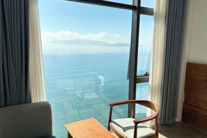 Une pièce dotée d’une grande fenêtre donnant sur une étendue d’eau, d’une table en bois et d’une chaise.