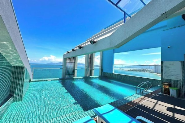 Un área de piscina con agua azul cristalina, techo de vidrio y vista al mar.