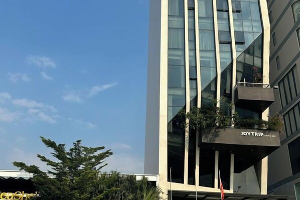A modern building with a glass facade and a sign that reads 'JOYTRIP Hotel'.