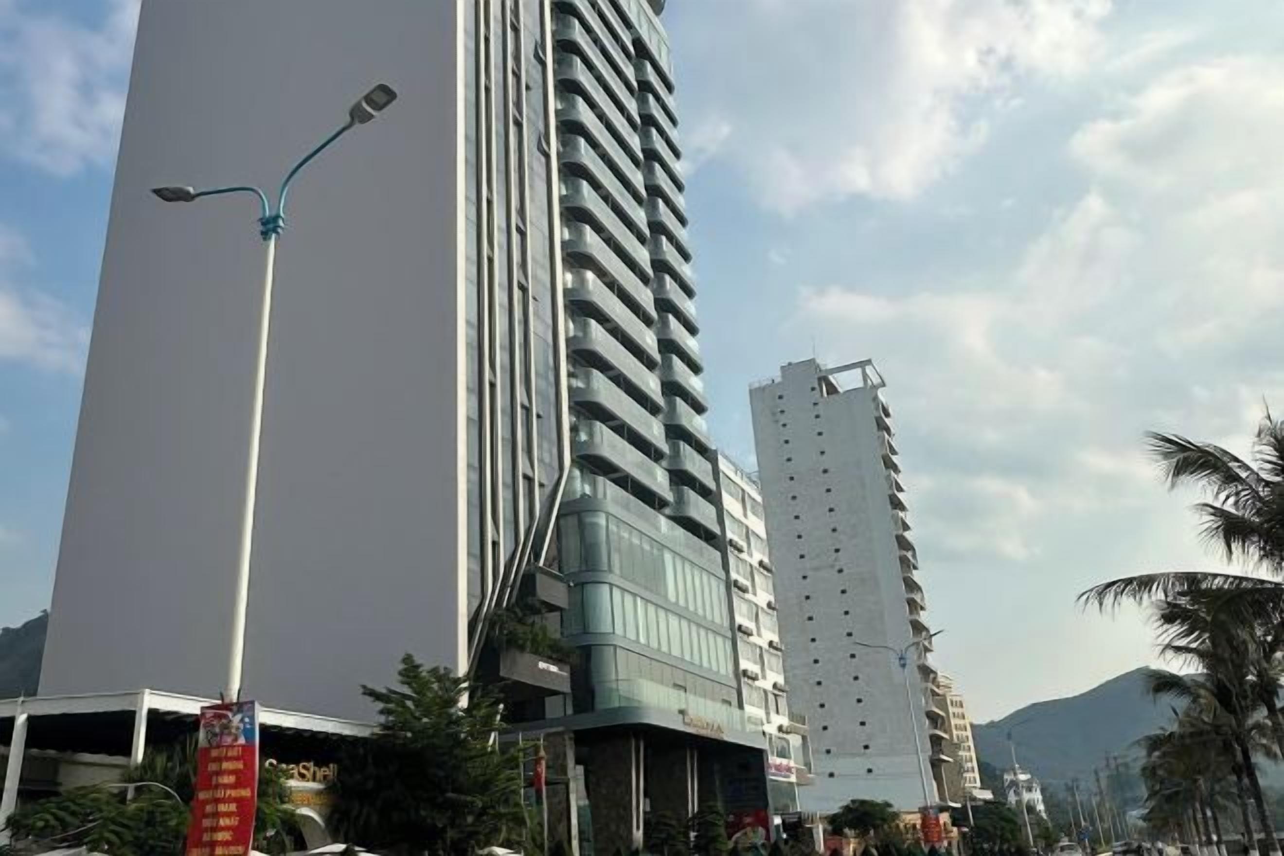 A tall building with a modern design, featuring a prominent glass facade and a series of balconies.