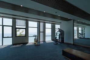Une salle de sport équipée de matériel d’exercice, dotée de grandes fenêtres et offrant une vue sur l’extérieur.