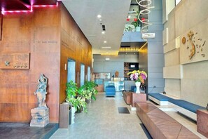 Vestíbulo de hotel con mostrador de recepción, zonas de estar y una estatua.
