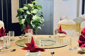 Une table dressée pour le dîner, avec de la belle verrerie, des serviettes rouges et un centre de table en verre.