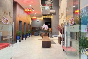 A hotel lobby with a reception desk, seating area, and a staircase.