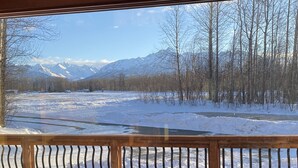 A view from a wooden deck overlooking a snow-covered landscape with a river and mountains in the background. - Lazy Mountain View- Spacious log home with mountain views, just north of Palmer (Palmer)