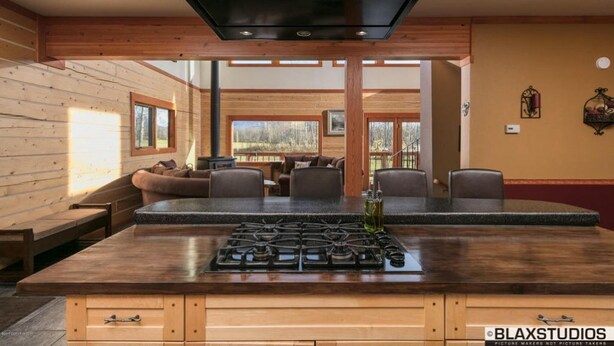A modern kitchen with a central island, wooden walls, and a view of the outdoors. - Lazy Mountain View- Spacious log home with mountain views, just north of Palmer (Palmer)