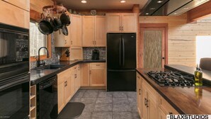 A modern kitchen with wooden cabinets, a black refrigerator, and a gas stove. - Lazy Mountain View- Spacious log home with mountain views, just north of Palmer (Palmer)