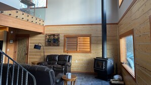 A spacious living area with a high ceiling, wooden walls, a fireplace, a sofa, and a staircase. - Lazy Mountain View- Spacious log home with mountain views, just north of Palmer (Palmer)