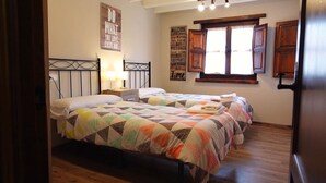 Un dormitorio con dos camas, suelo de madera, una ventana con cortinas y una pared con citas motivacionales.
