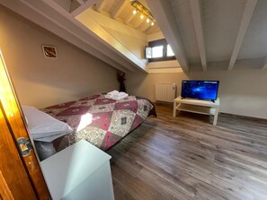 Ein Schlafzimmer mit einem Bett, einem Fernseher auf einem Schrank, einem Heizkörper und einem Fenster.