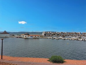 Una marina con barcos, un edificio de techo rojo y un cielo azul despejado.