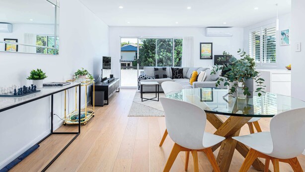 A modern living room with a glass dining table, white sofas, and a kitchen area with a chessboard. - Top Floor Apartment Close To Bondi Beach (Bondi)