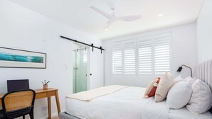 A modern bedroom with a bed, a desk, a chair, a ceiling fan, and a window with blinds. - Top Floor Apartment Close To Bondi Beach (Bondi)
