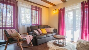 A cozy living room with a sofa, a rocking chair, a round coffee table, and a fluffy rug. - Vacation home Nina by Interhome (Fužine)