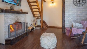 A cozy living room with a fireplace, wooden staircase, and a clock on the wall. - Vacation home Nina by Interhome (Fužine)