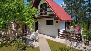 A two-story house with a red roof, a small porch with a bench, and a pathway leading to the entrance. - Vacation home Nina by Interhome (Fužine)