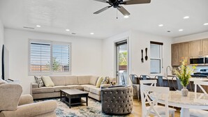 A modern living room with a sofa, ottoman, coffee table, and dining area with chairs and a table. - Santa Clara Comfort #39 by RedAwning (Santa Clara)