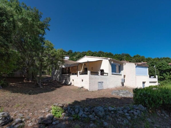 A single-story house with a sloped roof, a covered patio, and a stone wall in the foreground. - Pietralunga 8 by Interhome (Sotta)