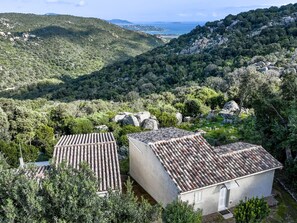 A hillside property with two white buildings featuring terracotta roofs, surrounded by lush greenery and rocky terrain. - Pietralunga 8 by Interhome (Sotta)