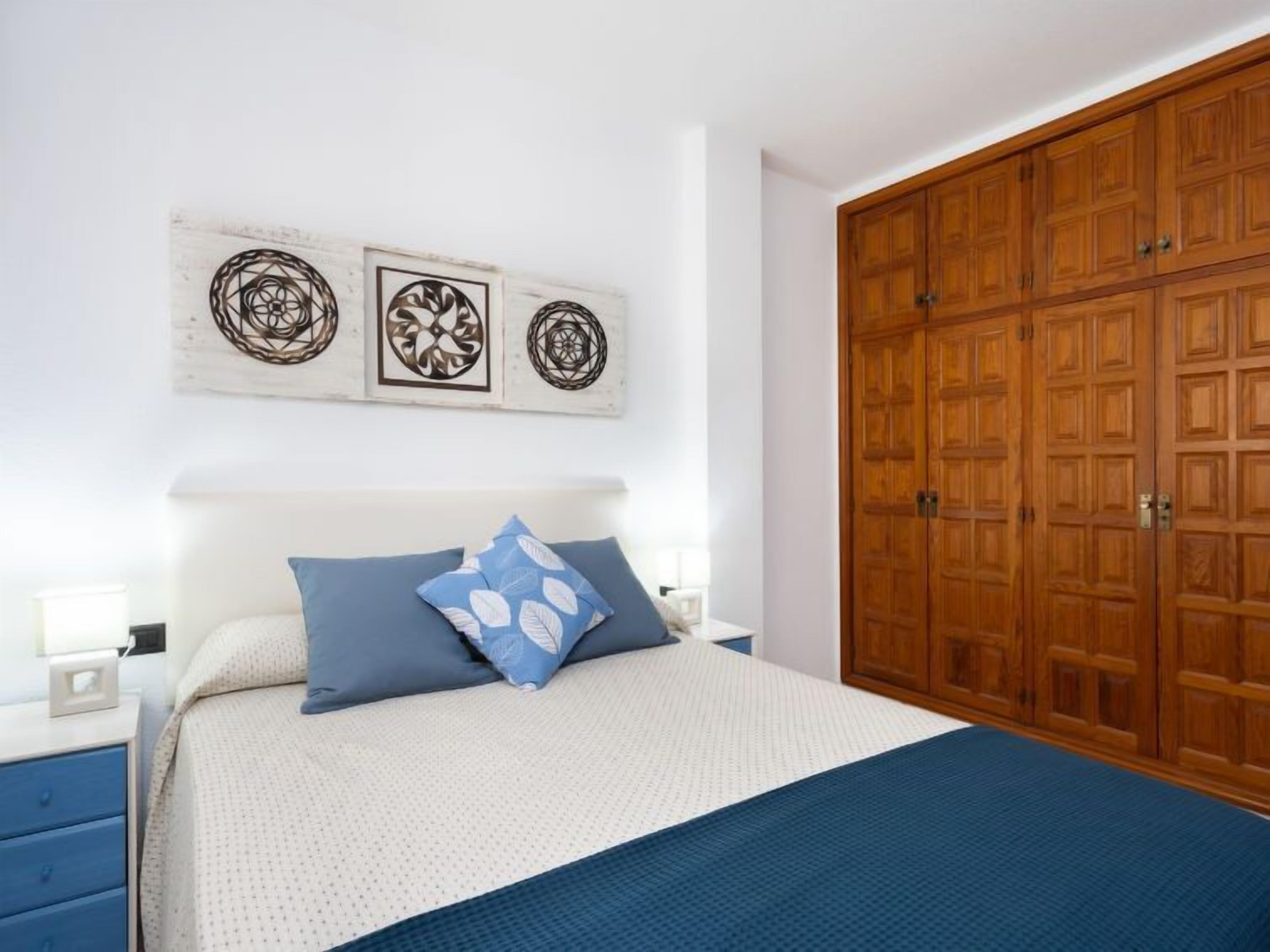 A bedroom with a large bed, a wooden wardrobe, and decorative wall art.