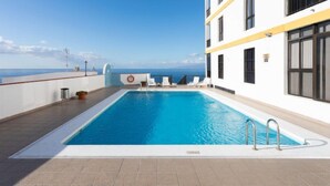 Una piscina sul tetto con acqua cristallina, pareti bianche e vista sull'oceano.