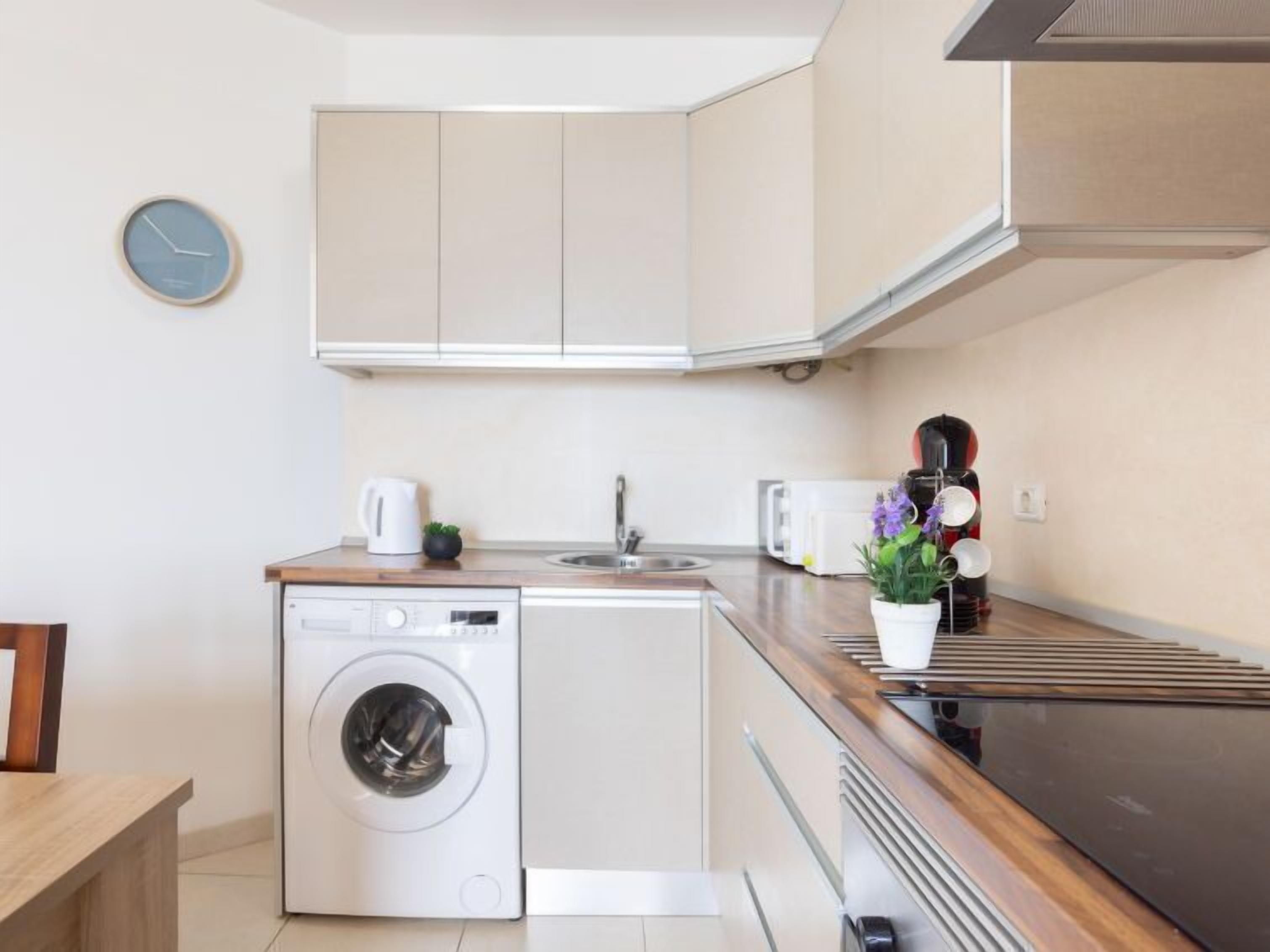Een kleine keuken met een wasmachine, een spoelbak en een magnetron.