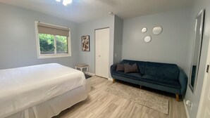 A bedroom with a bed, a blue sofa, a small table, and a door. - Newly Renovated - Suite Springs (Yellow Springs)