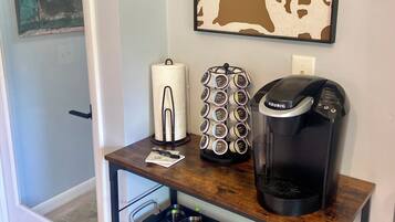 A kitchenette with a coffee maker, a paper towel holder, and a small cabinet with a drawer.