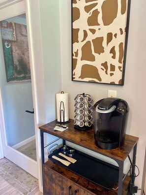 A kitchenette with a coffee maker, a paper towel holder, and a small cabinet with a drawer.