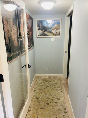 A hallway with a patterned floor, a framed landscape painting, and a door with a glass panel. - Newly Renovated - Suite Springs (Yellow Springs)